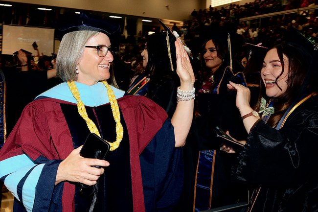 Outgoing WHC Chancellor Kristin Clark high fives Lemoore College grads.